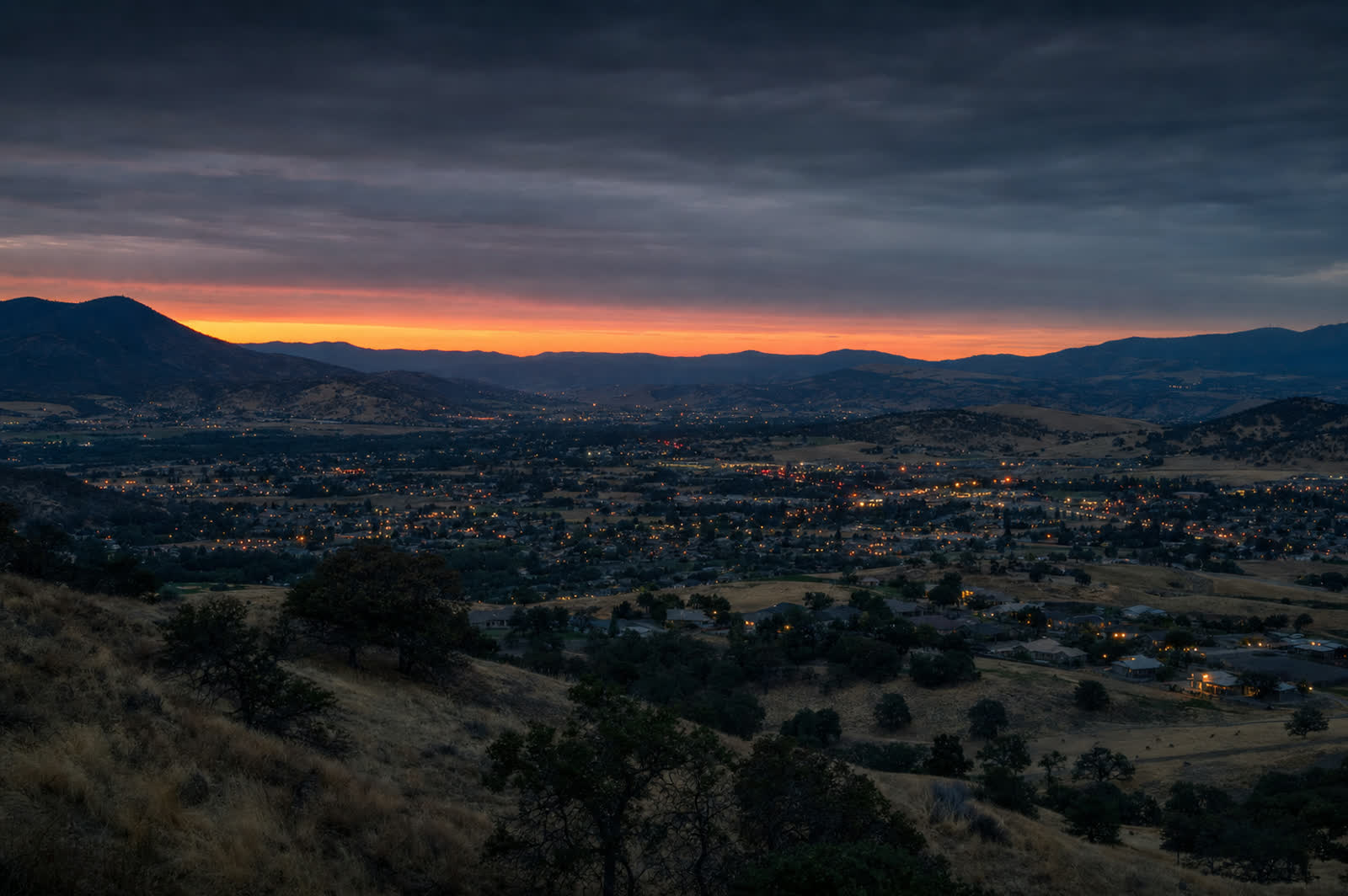 The Rogue Valley at dusk, with residential neighborhoods spread below oak-covered hills near Medford, Oregon